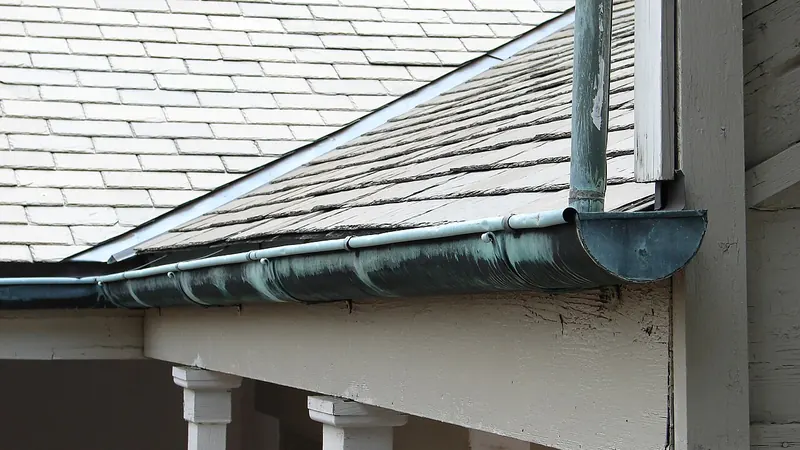 Metal gutter and round downspout at the eave of a 19th-century house